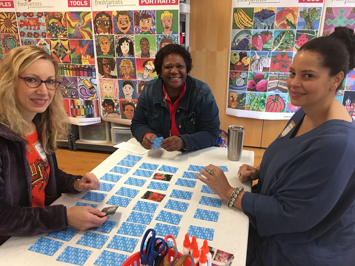 Three women sitting at a table playing a game